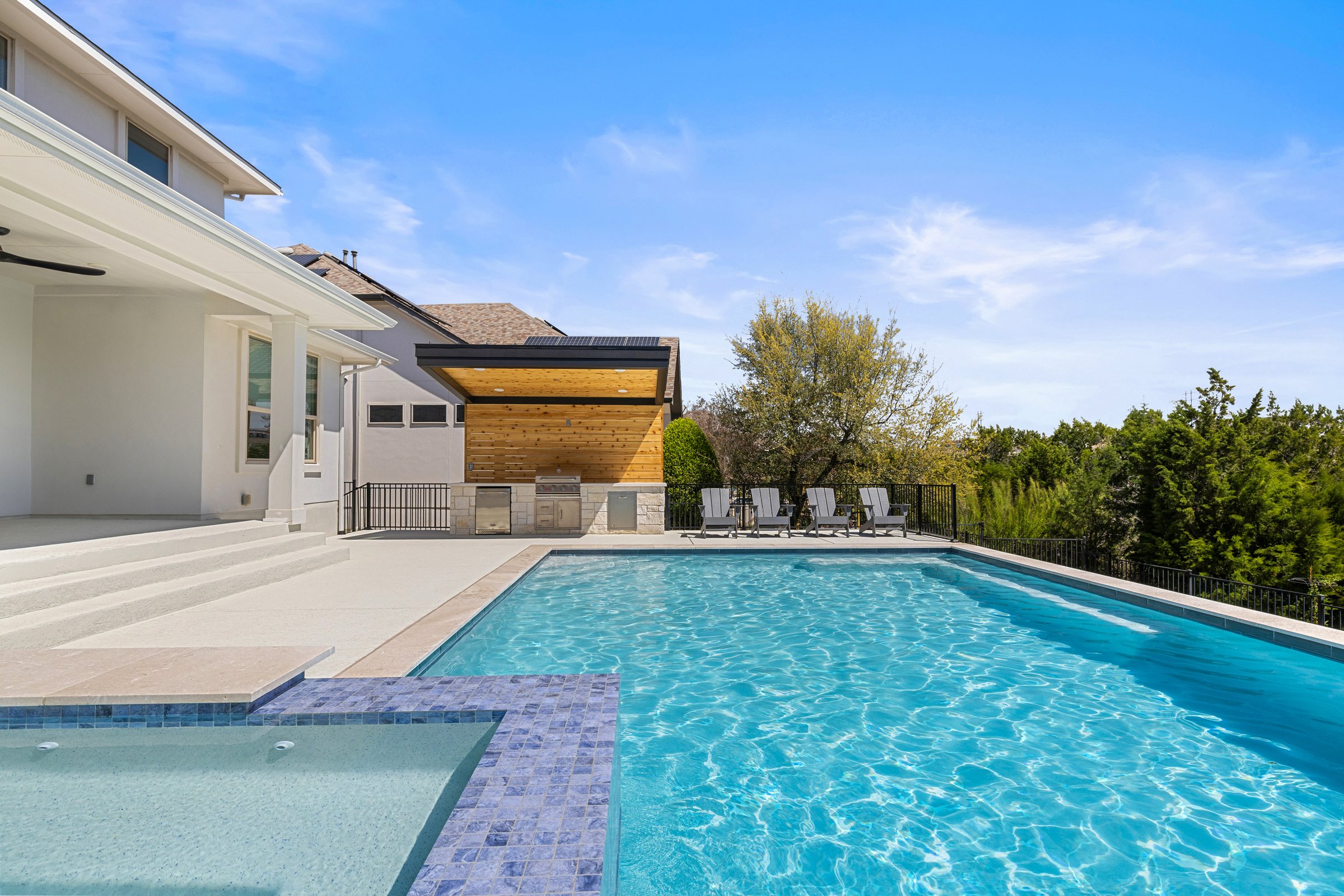 Azure Terrace entertaining pool deck with outdoor kitchen and lounge area under open sky in Austin TX