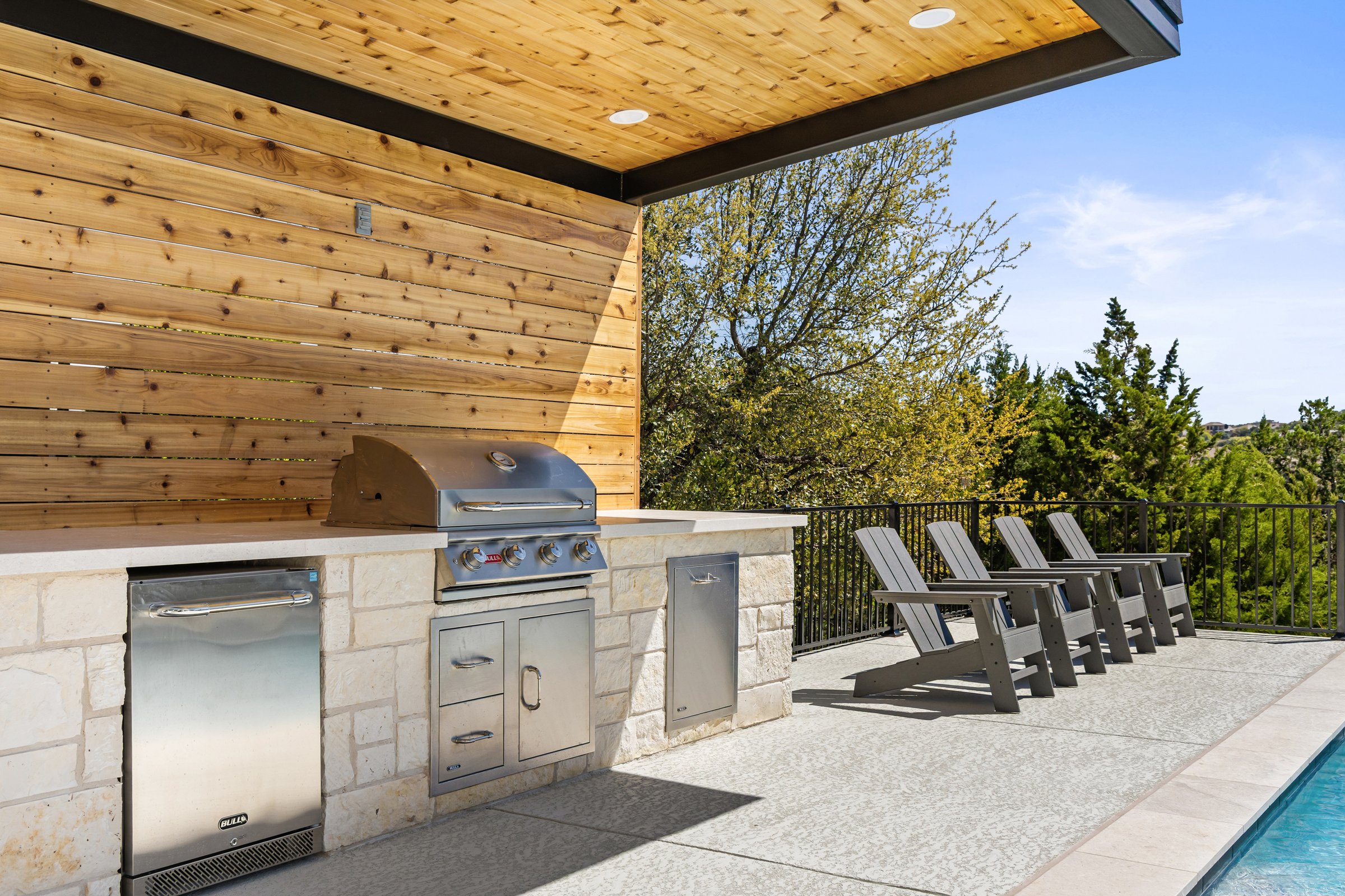 Azure Terrace outdoor kitchen with built in grill and lounge chairs overlooking pool in Austin TX
