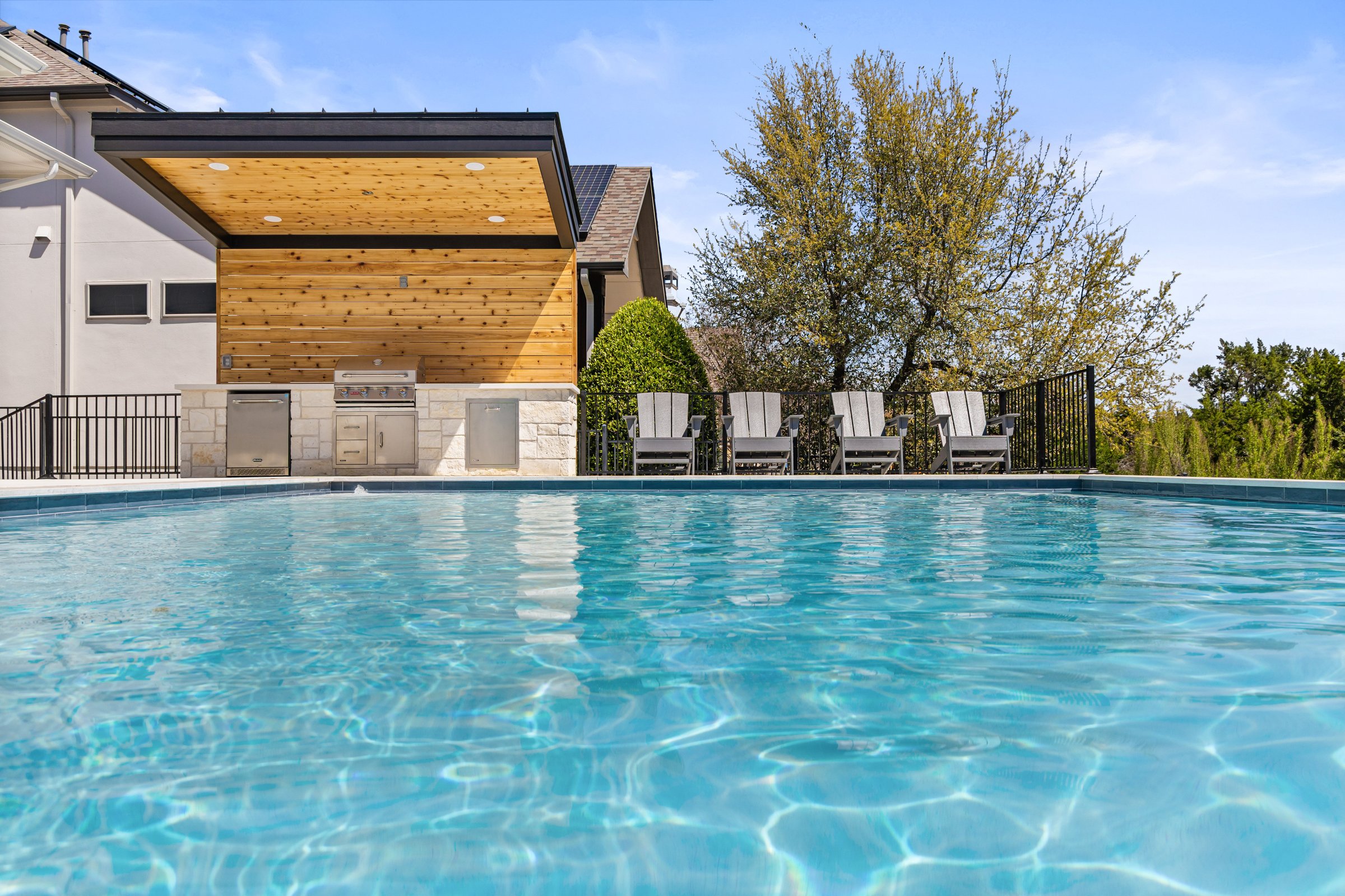 Azure Terrace modern pool at water level with outdoor kitchen and lounge chairs in Austin TX