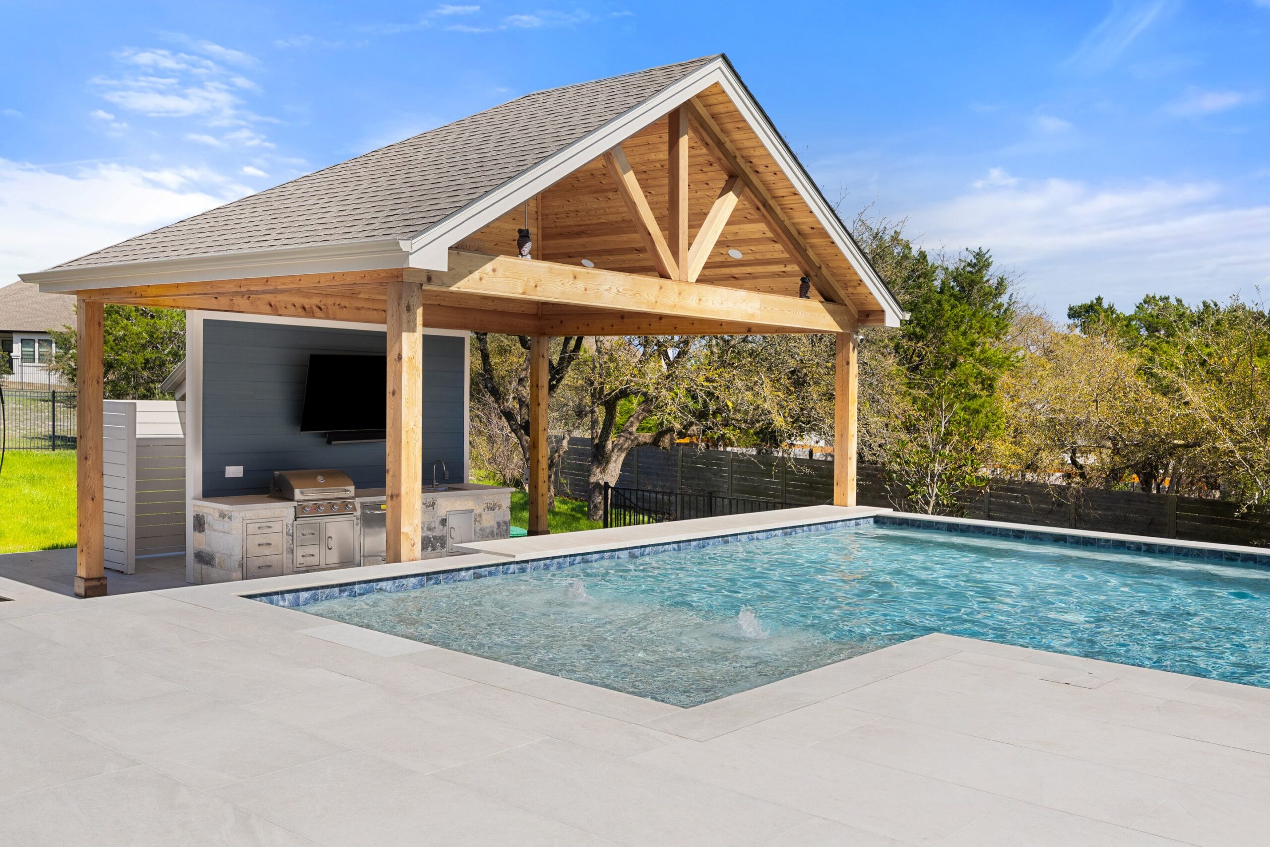 Stratus Grove outdoor kitchen with built-in grill and TV under cedar pavilion, poolside swim-up bar design, Wild Basin Pools Austin TX