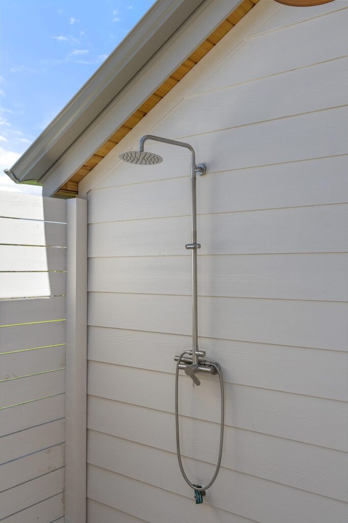 Outdoor shower station on cedar pavilion exterior at Stratus Grove, custom pool build by Wild Basin Pools Austin TX