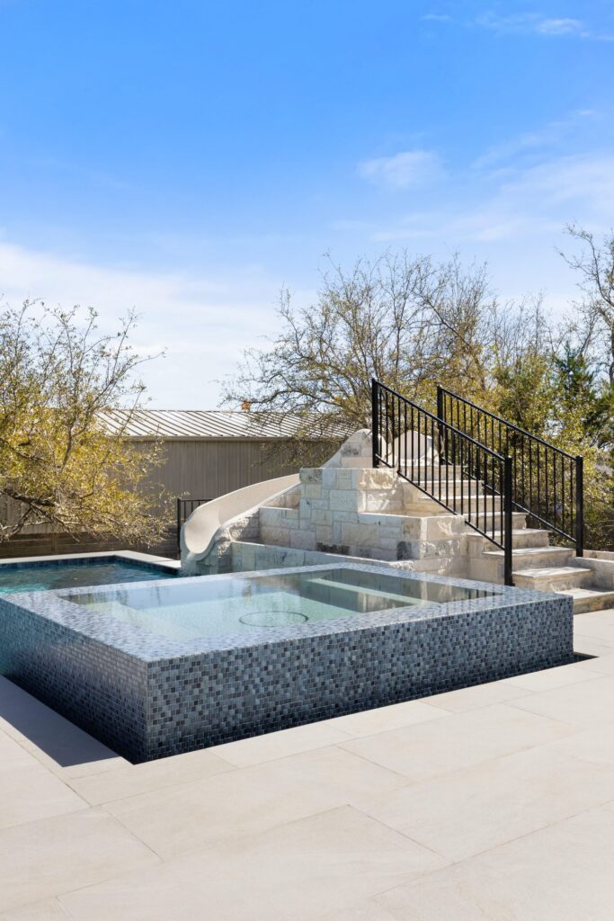 Stratus Grove raised spa with blue glass tile and custom water slide, geometric pool design by Wild Basin Pools Austin TX