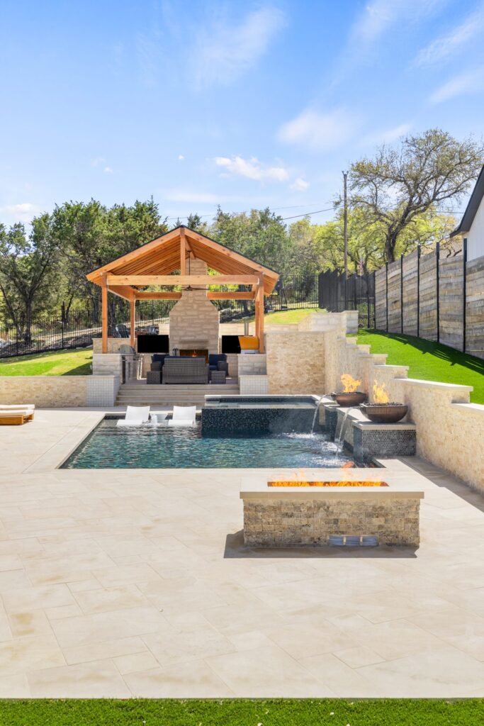 Covered patio with outdoor dining area overlooking The Commons pool and fire bowl water features by Wild Basin Pools Austin TX