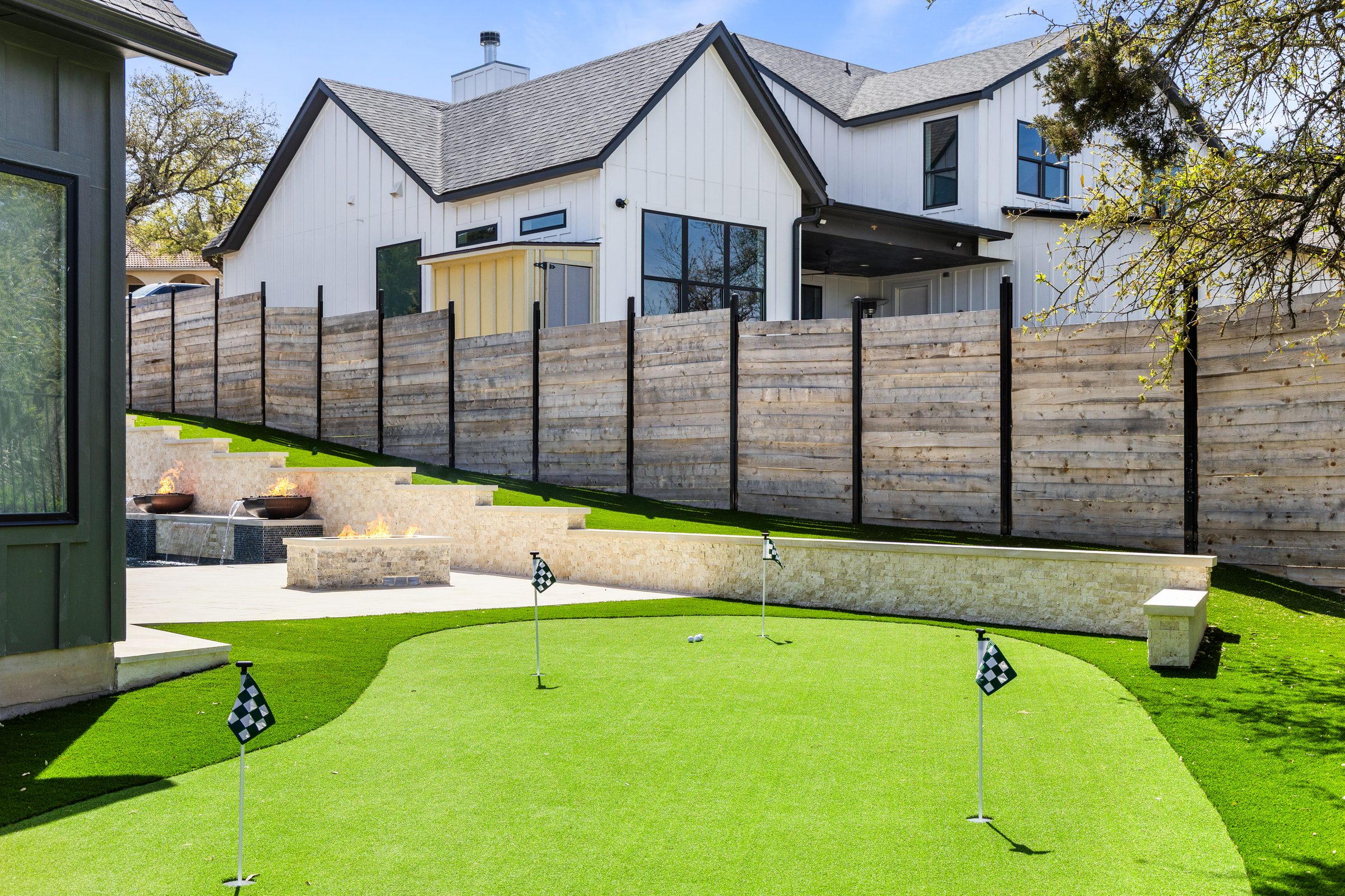 Wide view of The Commons fire pit seating area with covered pavilion and pool in the background by Wild Basin Pools Austin TX