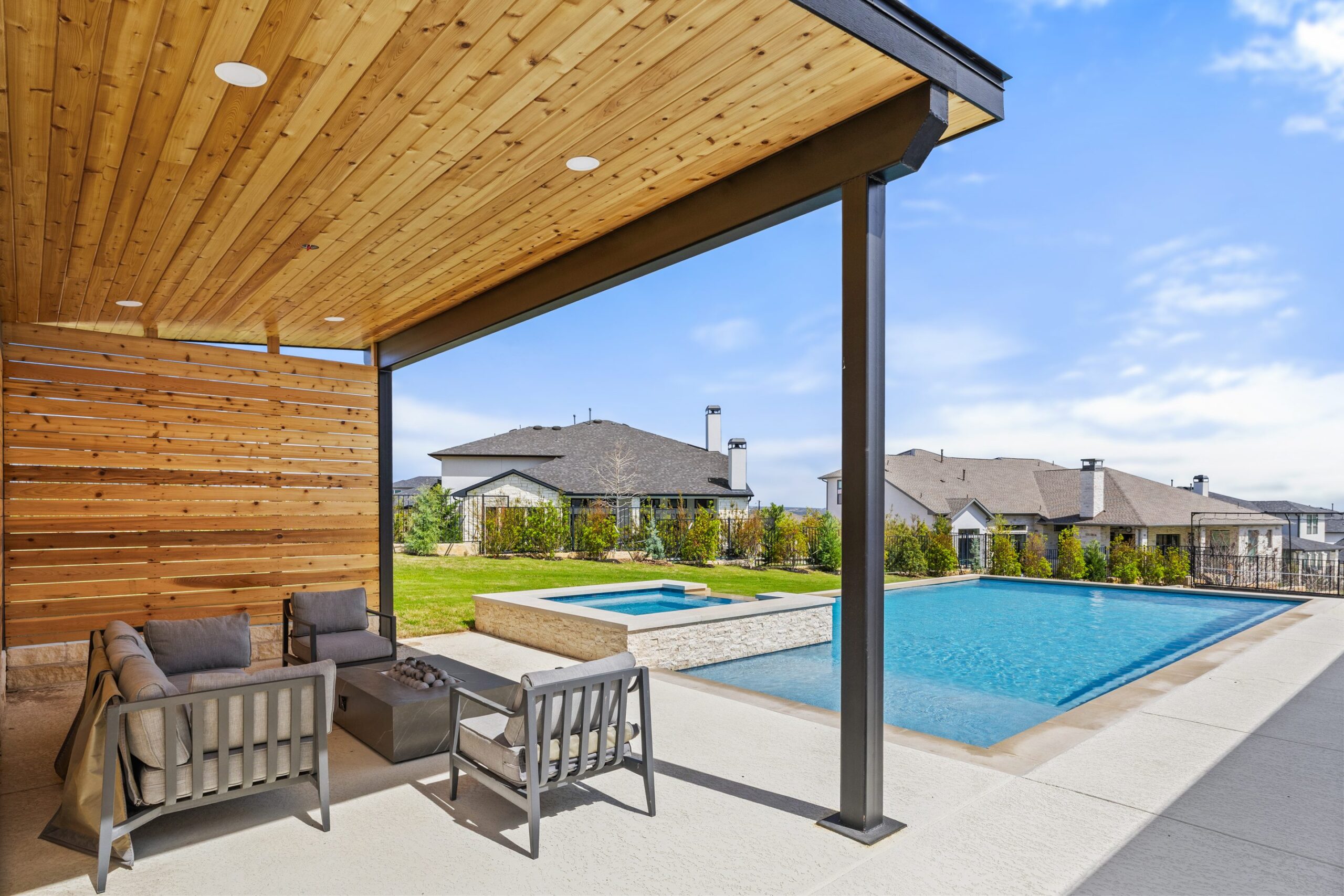 Cedar slatted lounge cabana with modern fire pit seating area and pool view at The Backyard Club Wild Basin Pools Austin TX