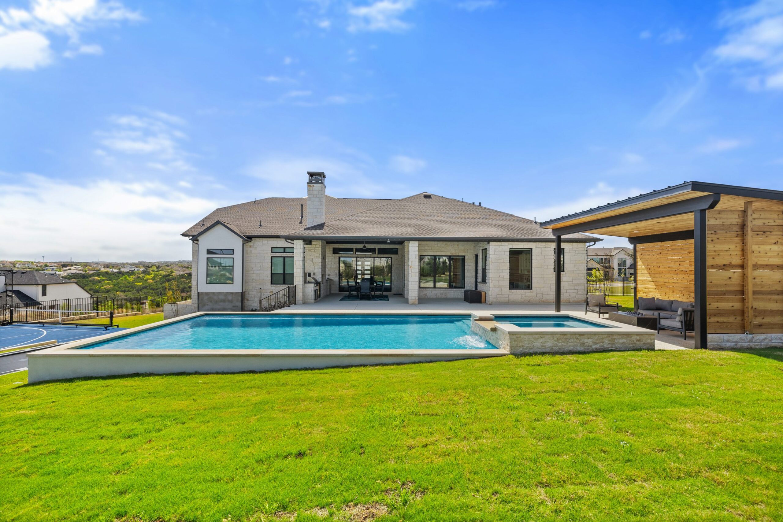Ground level view of The Backyard Club pool and basketball court with Hill Country views by Wild Basin Pools Austin TX