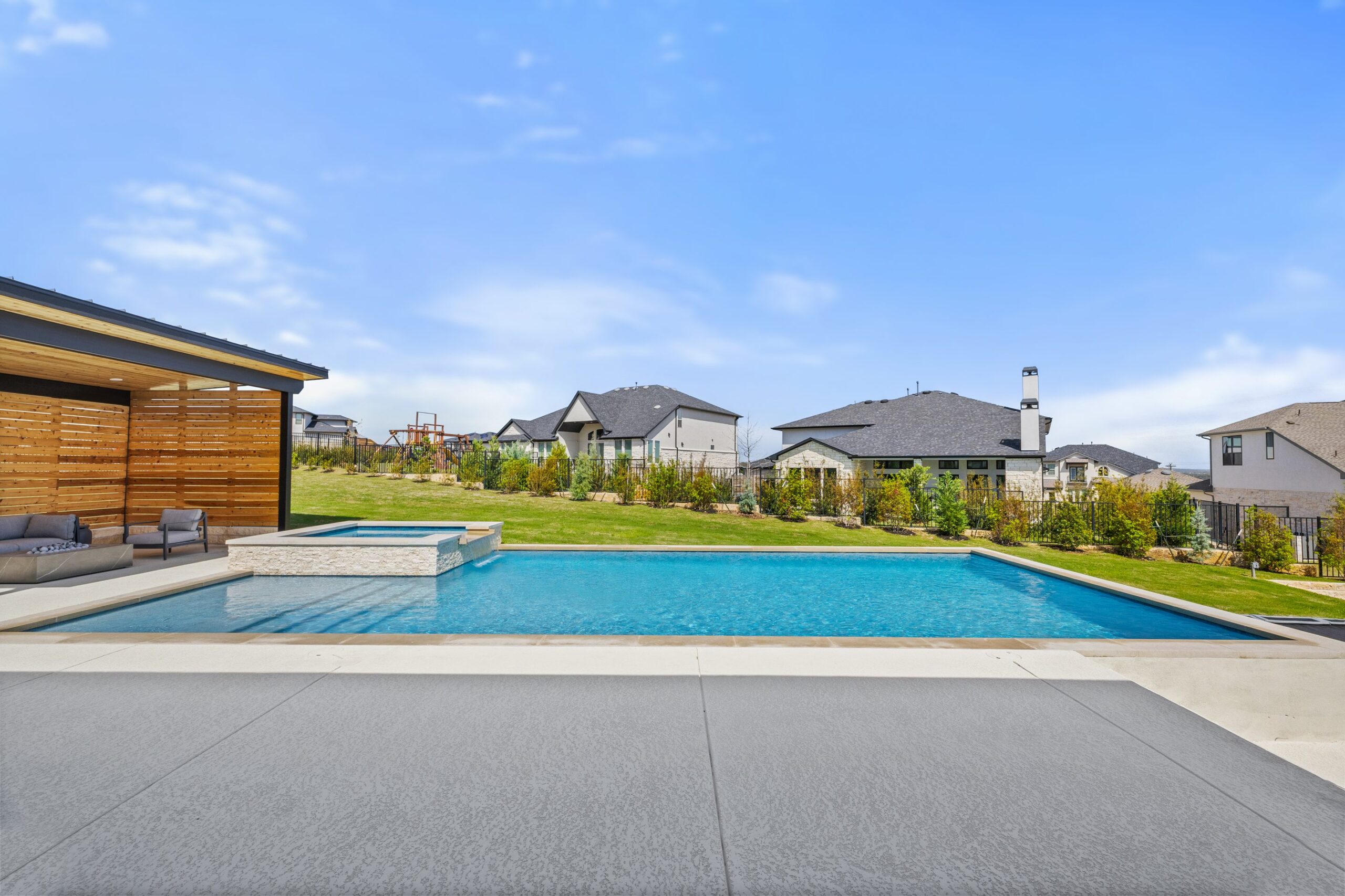 Rear elevation of The Backyard Club showing geometric pool raised spa and cedar lounge cabana by Wild Basin Pools Austin TX
