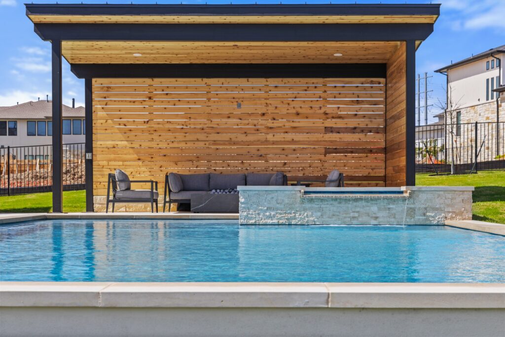 Raised spa with travertine stone veneer and sheet waterfall spillover at The Backyard Club by Wild Basin Pools Austin TX