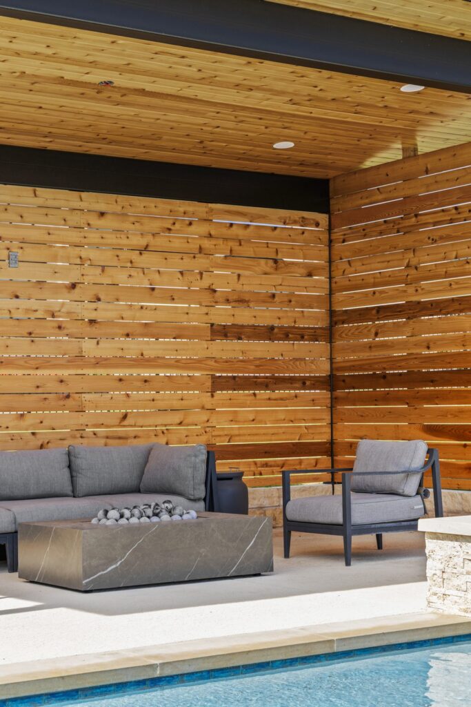 Cedar slatted lounge walls with modern fire pit and outdoor seating at The Backyard Club Wild Basin Pools Austin TX